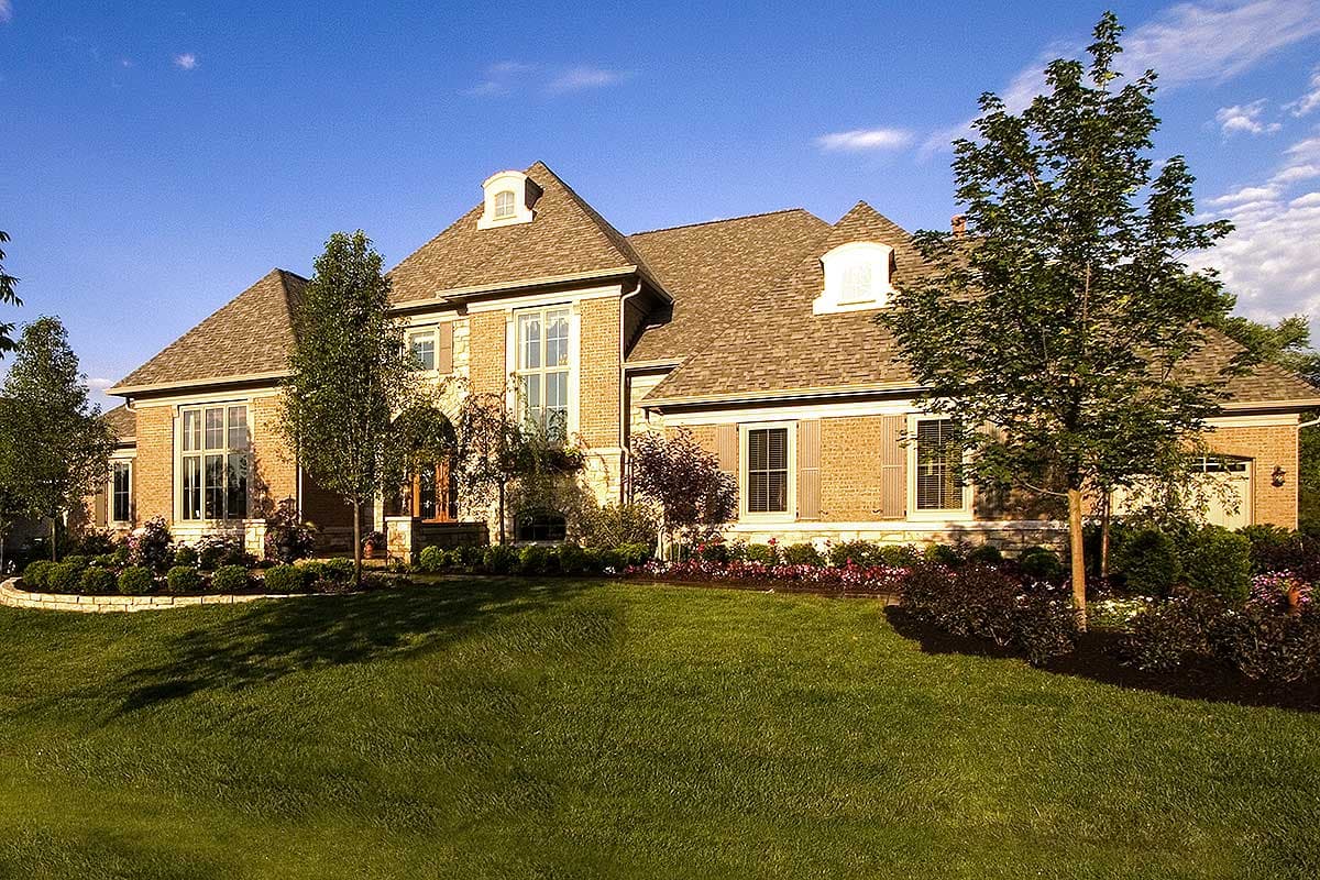 House plan exterior of a two-story brick home with arched entryway, multiple gables, dormers, and a multi-level roofline.