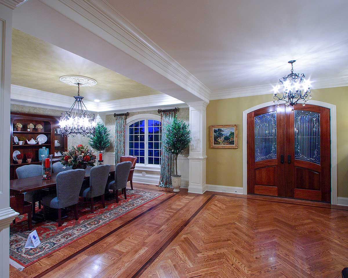 Dining room with a large wooden table, upholstered chairs, fireplace, and ornate double doors.