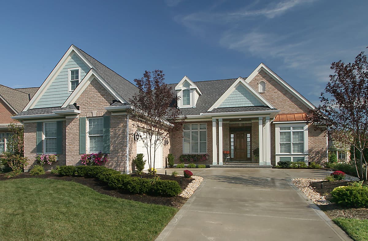 House plan exterior: One-story brick home with gabled dormers, covered entry with columns, and attached garage.