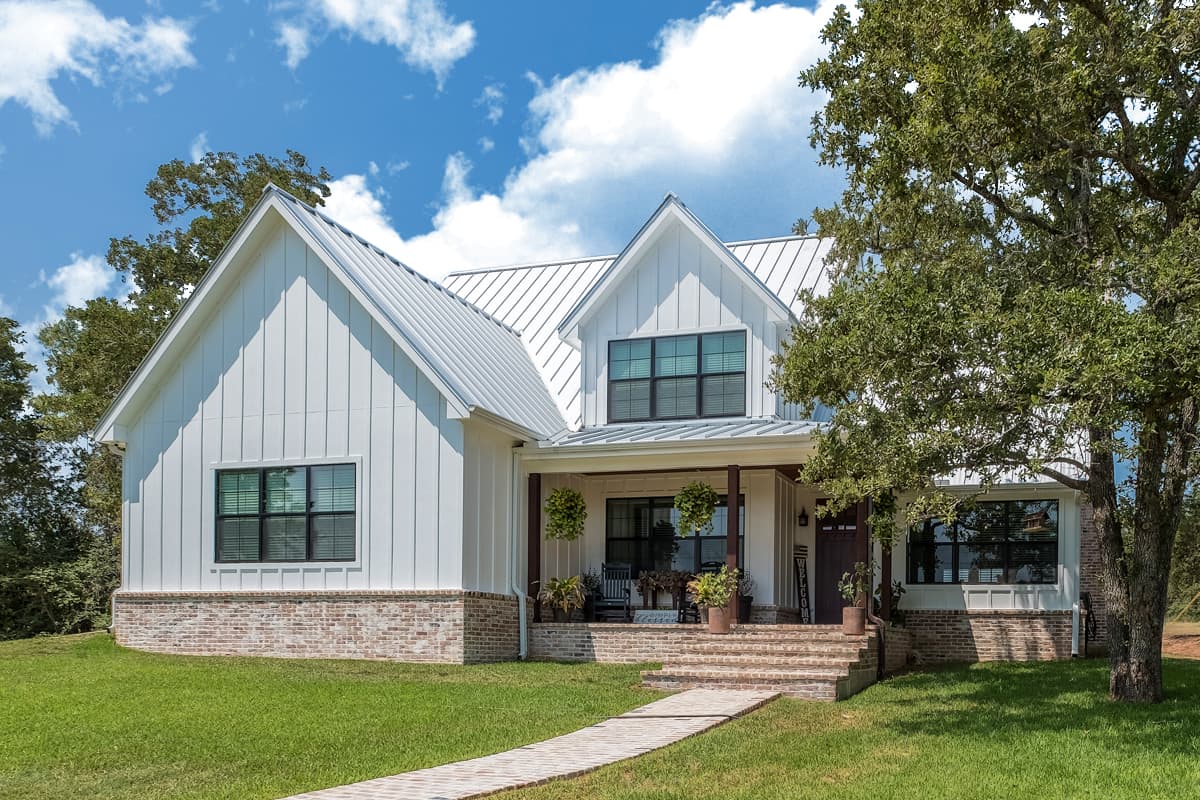 House plan exterior. Two-story Modern Farmhouse with gabled roof, brick foundation, front porch, and vertical siding.