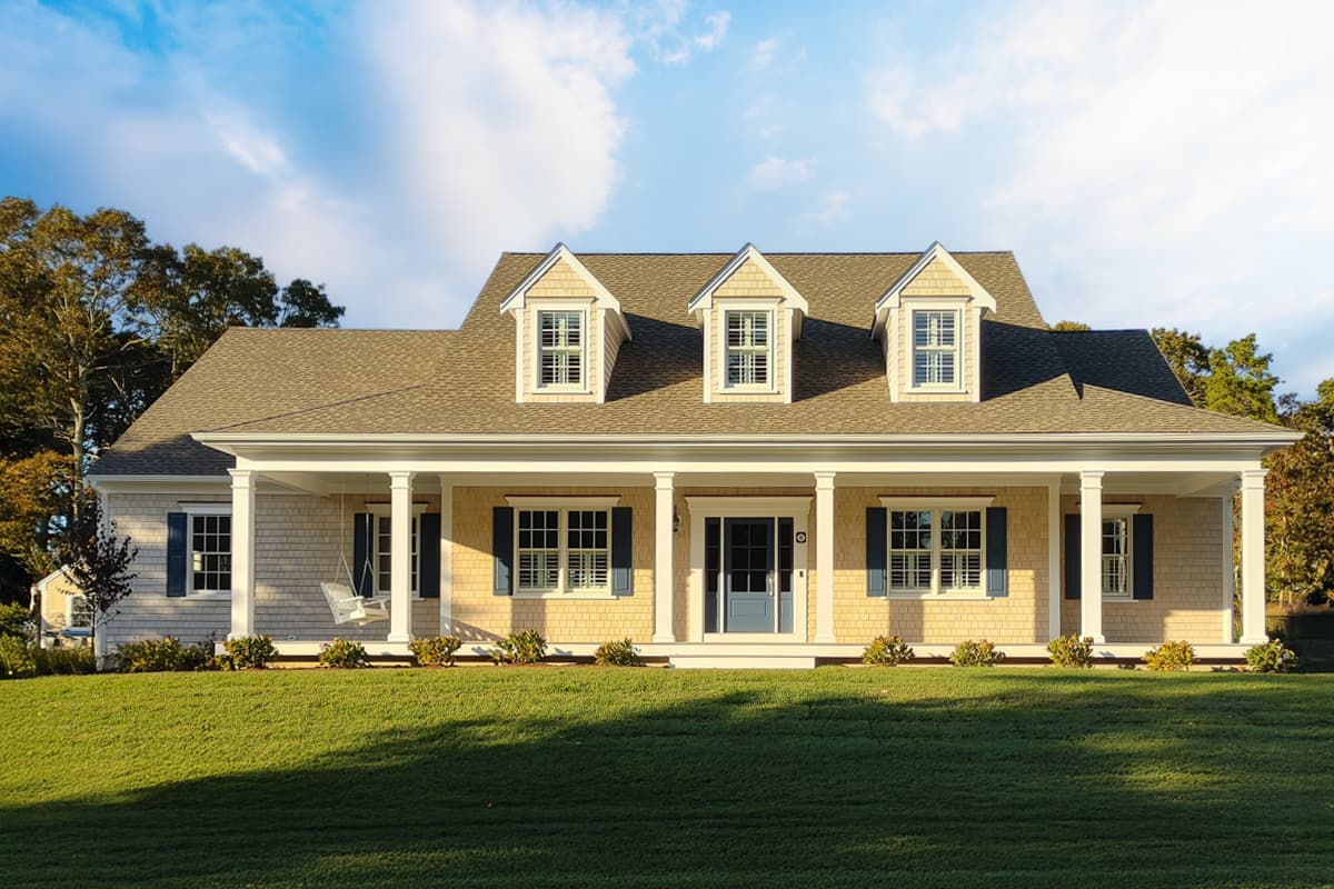 House plan exterior. Two-story Colonial-style home with a columned porch, three dormers, and a gabled roof. Exterior features clapboard siding.