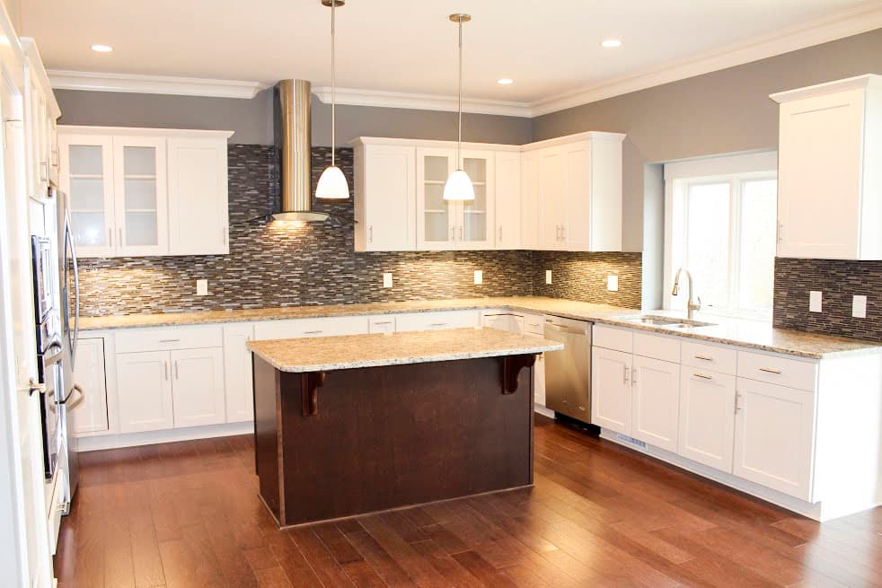 Kitchen with white cabinets, granite countertops, mosaic backsplash, stainless steel appliances, and a central island.