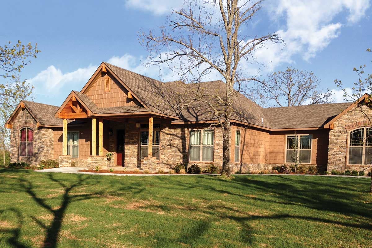 House plan exterior: Ranch style, one story with stone and wood siding, covered front porch with timber supports, and gabled dormers.