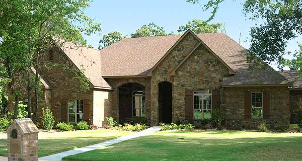House plan exterior: One-story home with stone and brick facade, arched entryway, gables, and multiple rooflines.
