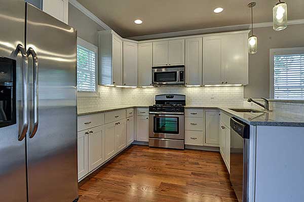 Kitchen with white cabinets, granite countertops, stainless steel appliances including a refrigerator, range, microwave, and dishwasher.