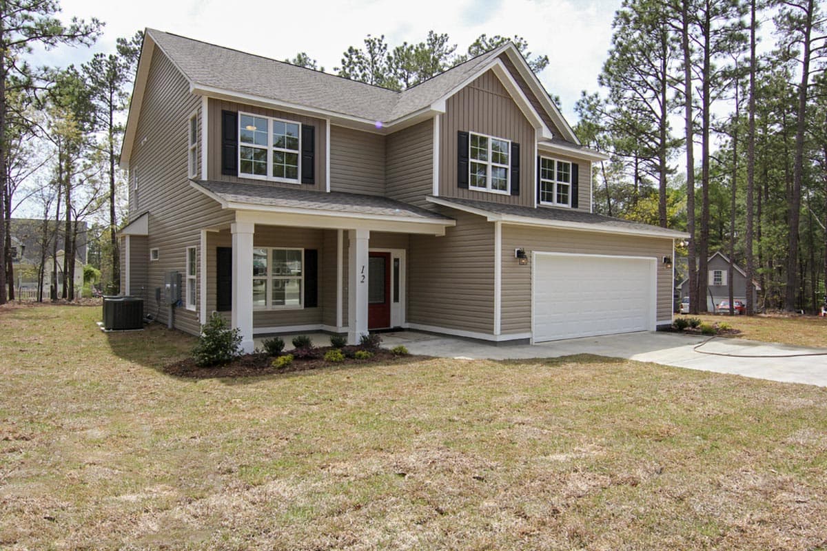 Two-story house plan exterior with covered front porch, white columns, red door, gable, and attached two-car garage.