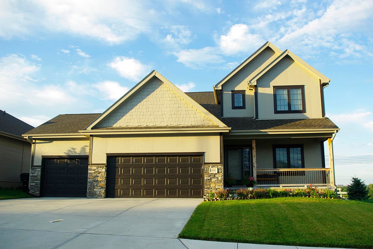 Two-story house plan exterior with a side-facing three-car garage, gabled rooflines, and a covered front porch.