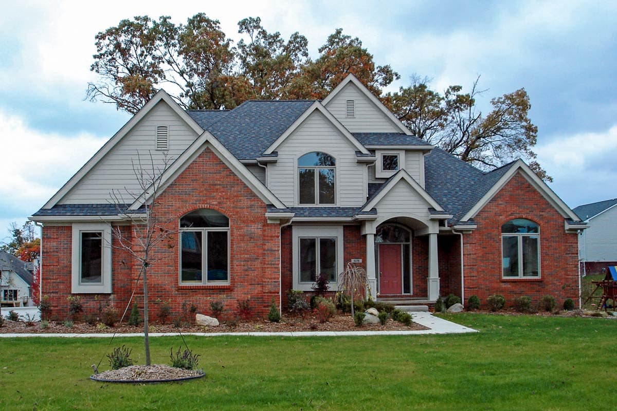 Two-story brick house plan exterior with gables, arched windows, and a covered entry with columns.