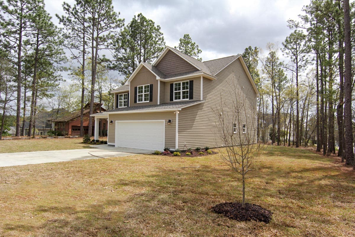 Two-story house plan exterior with vinyl siding, front-facing garage, gables, and white-paned windows.