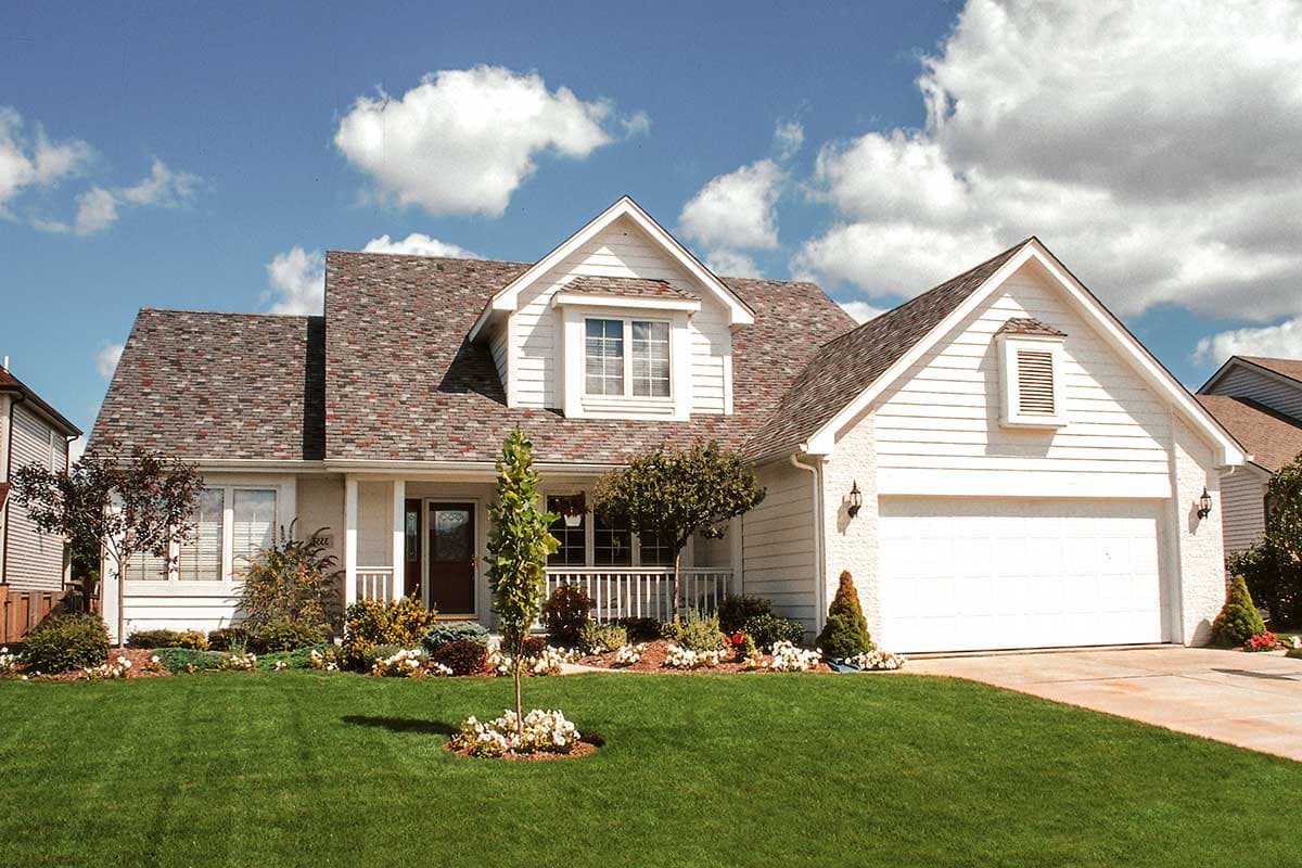 House plan exterior: Two-story modern farmhouse with front porch, gabled dormer, and side-facing garage.