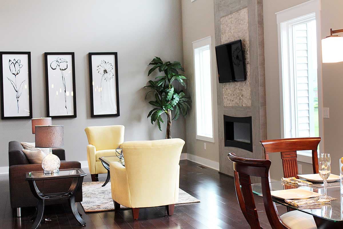 Living area with fireplace, seating, and dining table. Tall windows and modern art on wall.