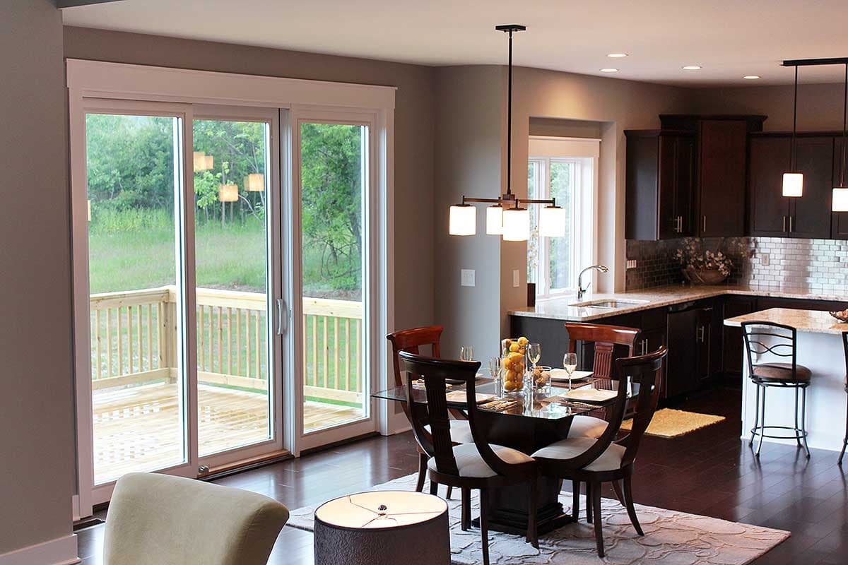 Open-concept dining area and kitchen with dark wood cabinets, granite countertops, and a sliding glass door leading to a wooden deck.
