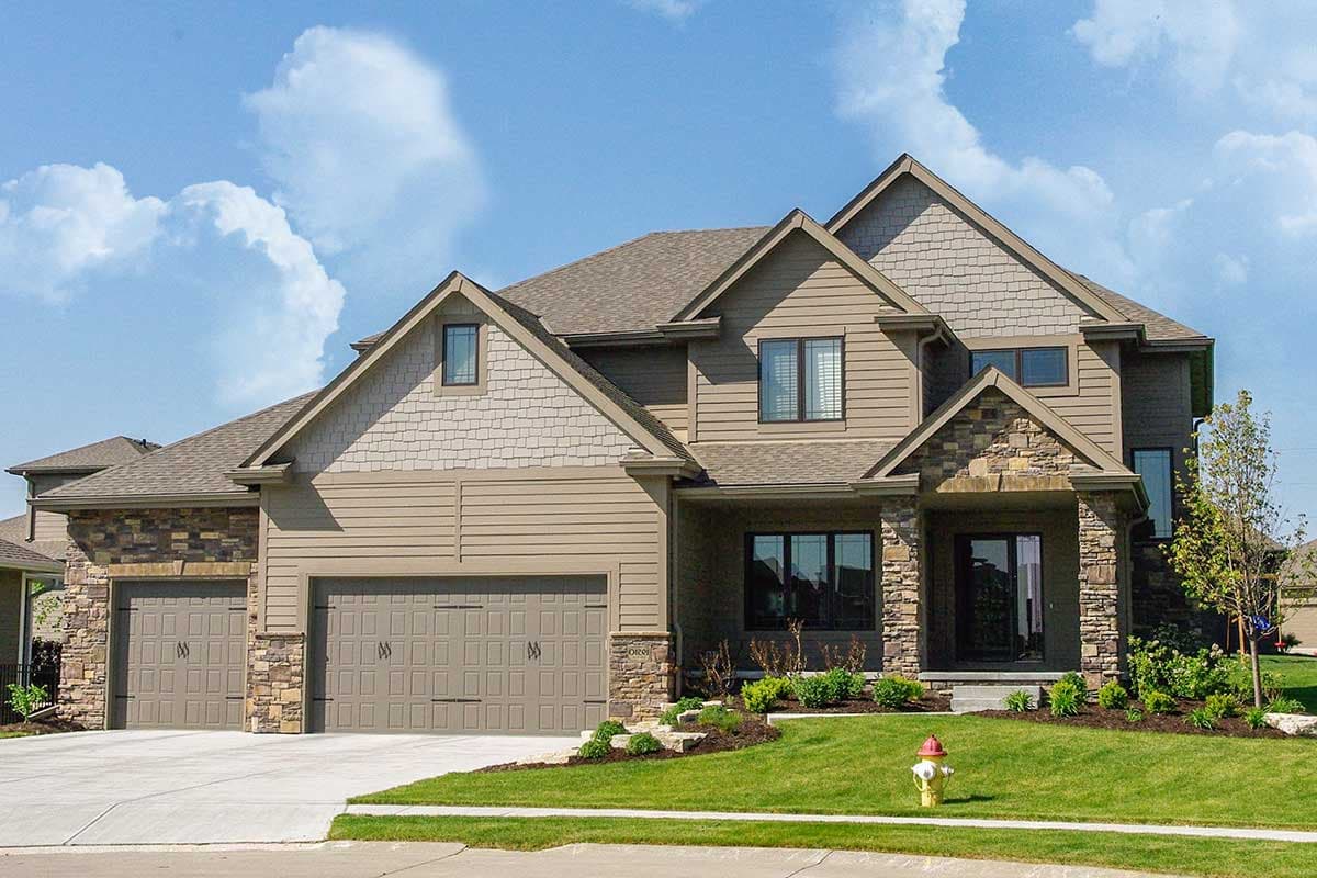 House plan exterior. Two-story, with stone accents and gabled rooflines. Features include a front porch, multiple dormers, and an attached garage.