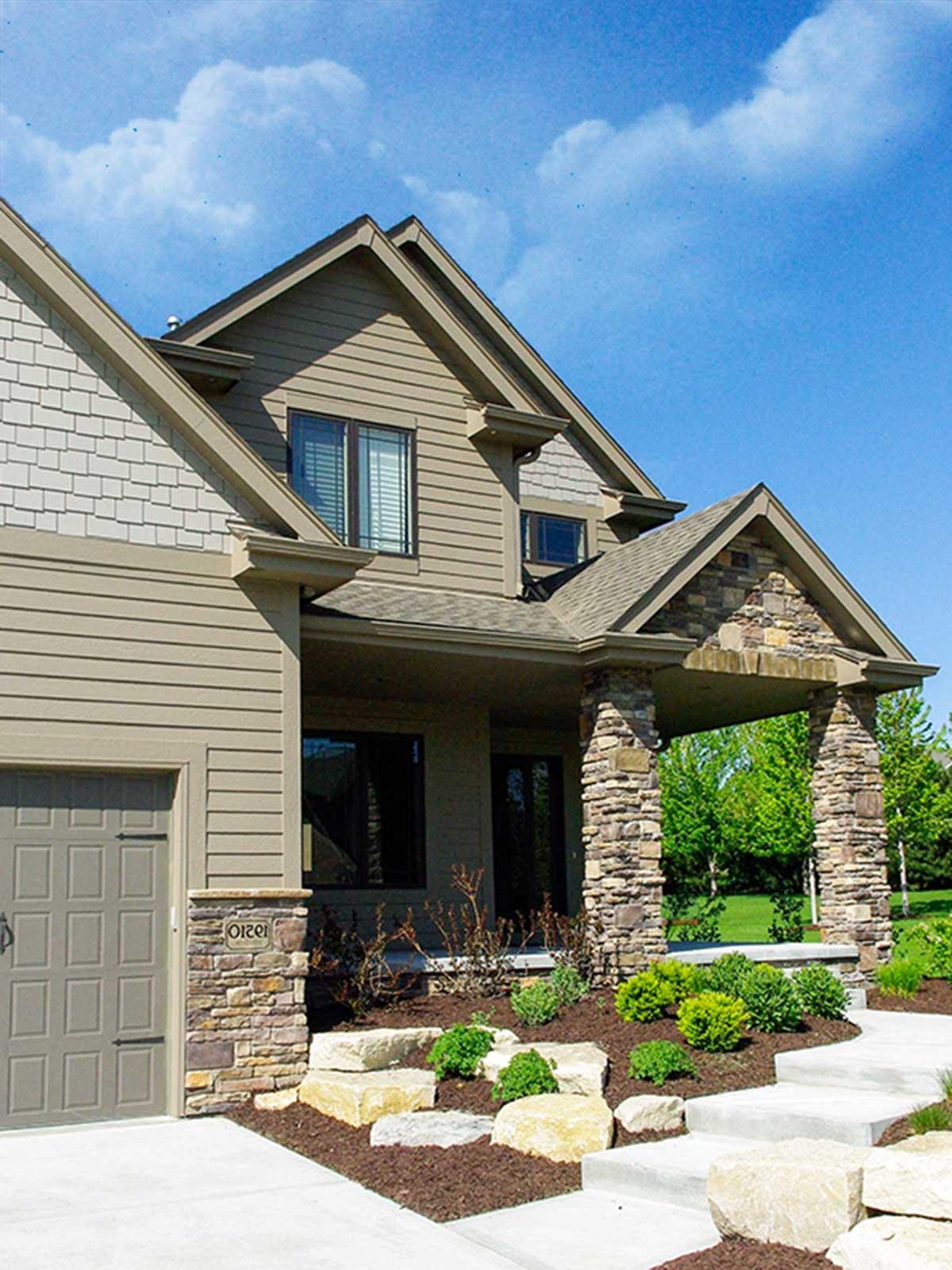 House plan exterior: Two-story home with siding, stone accents, gabled roof, and covered porch with stone pillars.