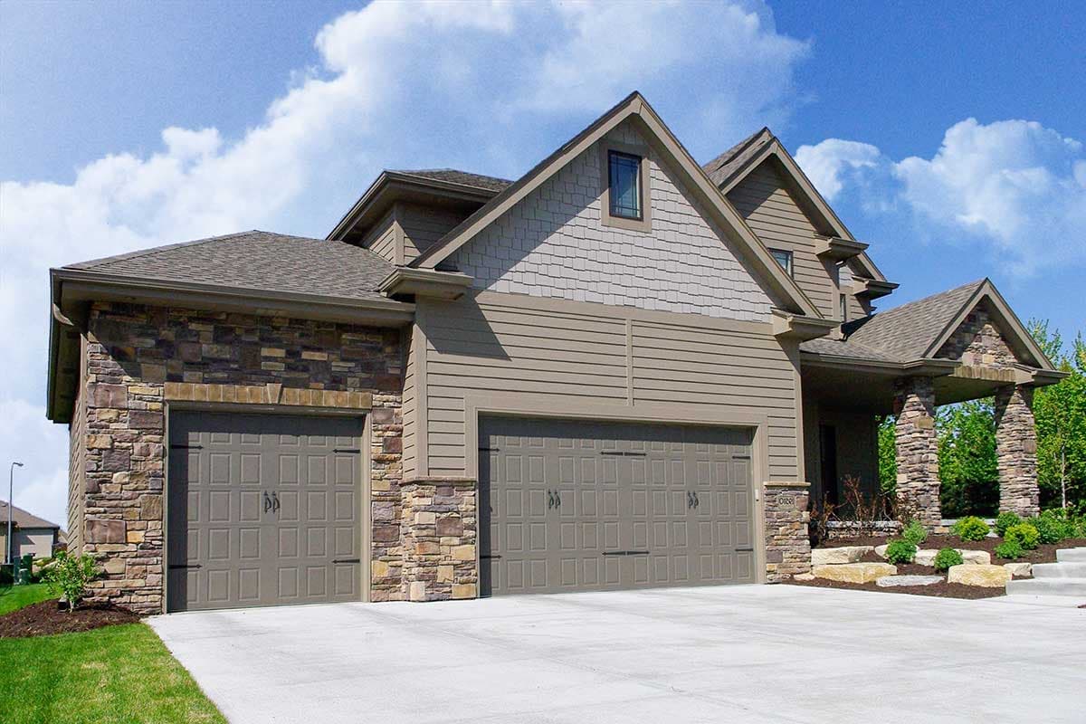 House plan exterior: Two-story home with stone accents, a covered porch with stone pillars, and a three-car garage.