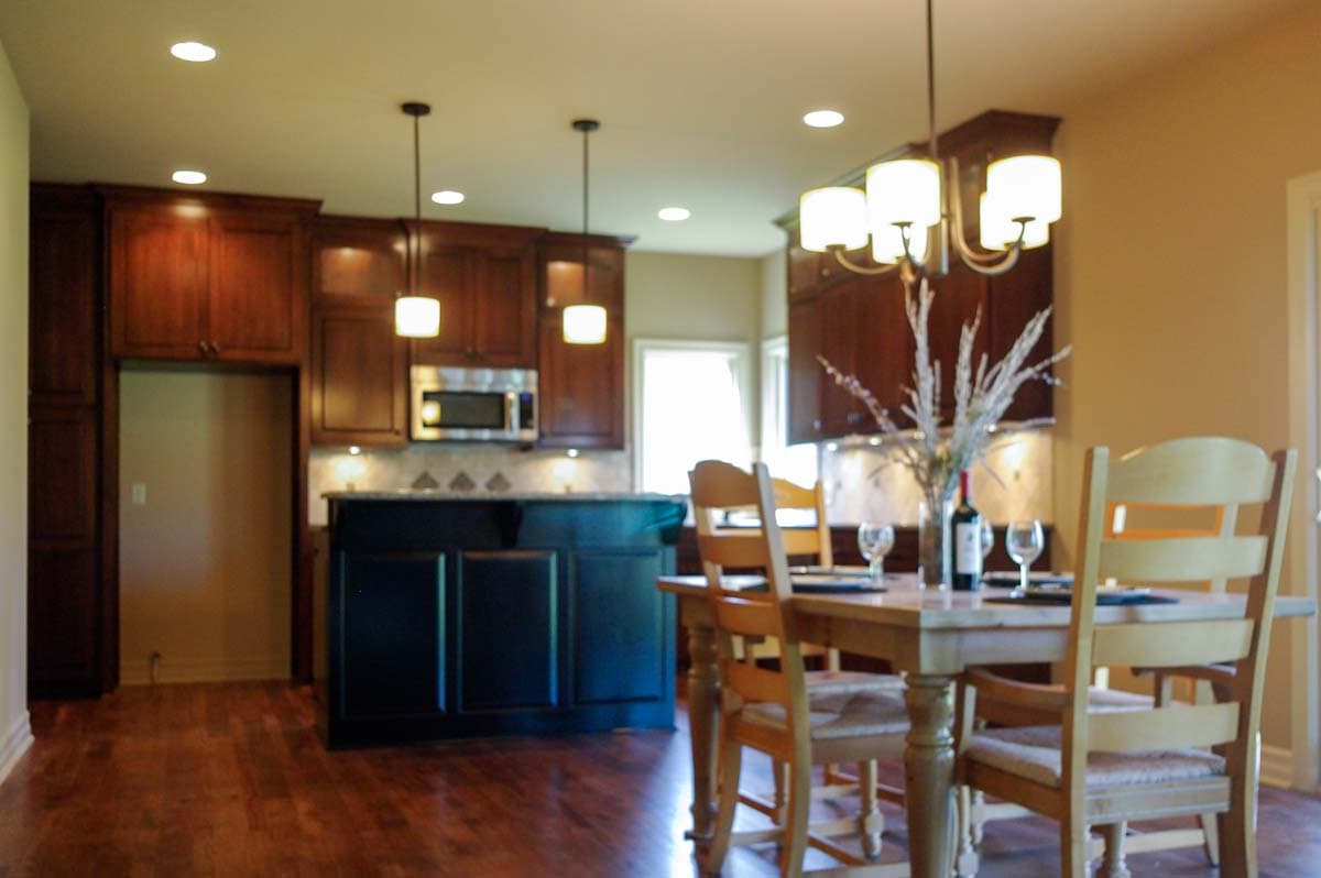 Kitchen and dining area with dark wood cabinets, island, and wooden dining table.