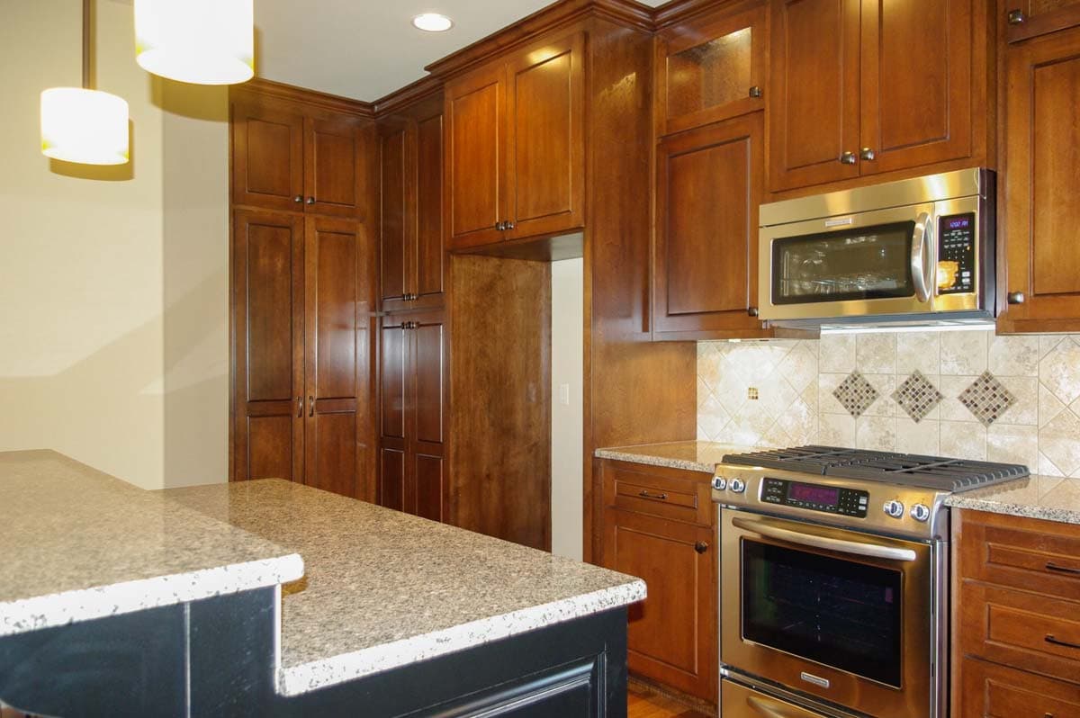 Kitchen with wood cabinetry, granite countertops, stainless steel range, and microwave.