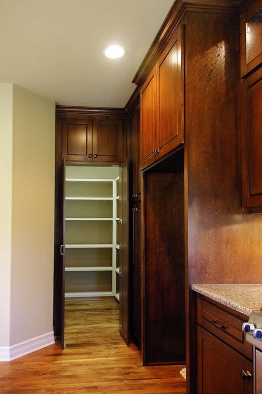 Kitchen pantry with open shelves and dark wood cabinetry, granite countertop, and hardwood flooring.