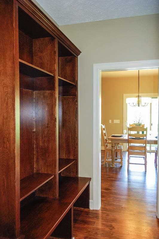 Built-in wooden shelving unit with bench, opening to dining area with table and chairs.