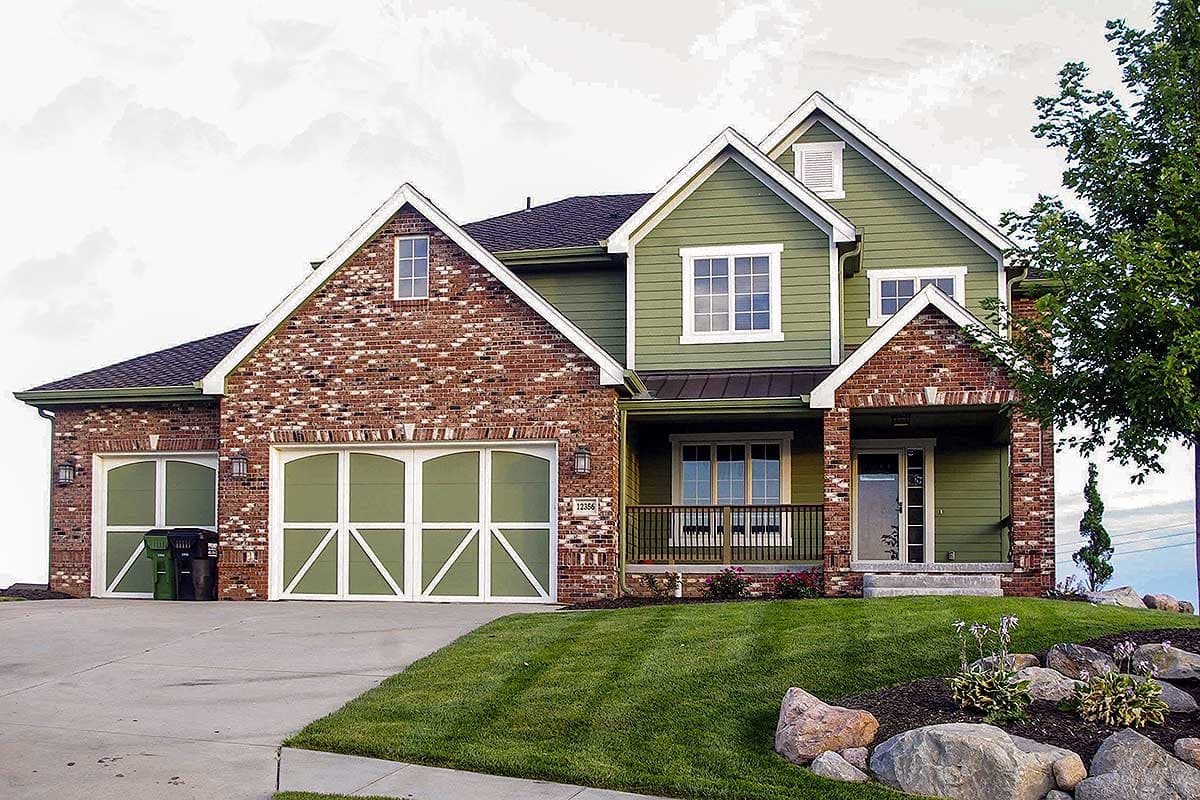 House plan exterior: Two-story home with brick and green siding, gable roofs, front-facing garage, and covered porch.