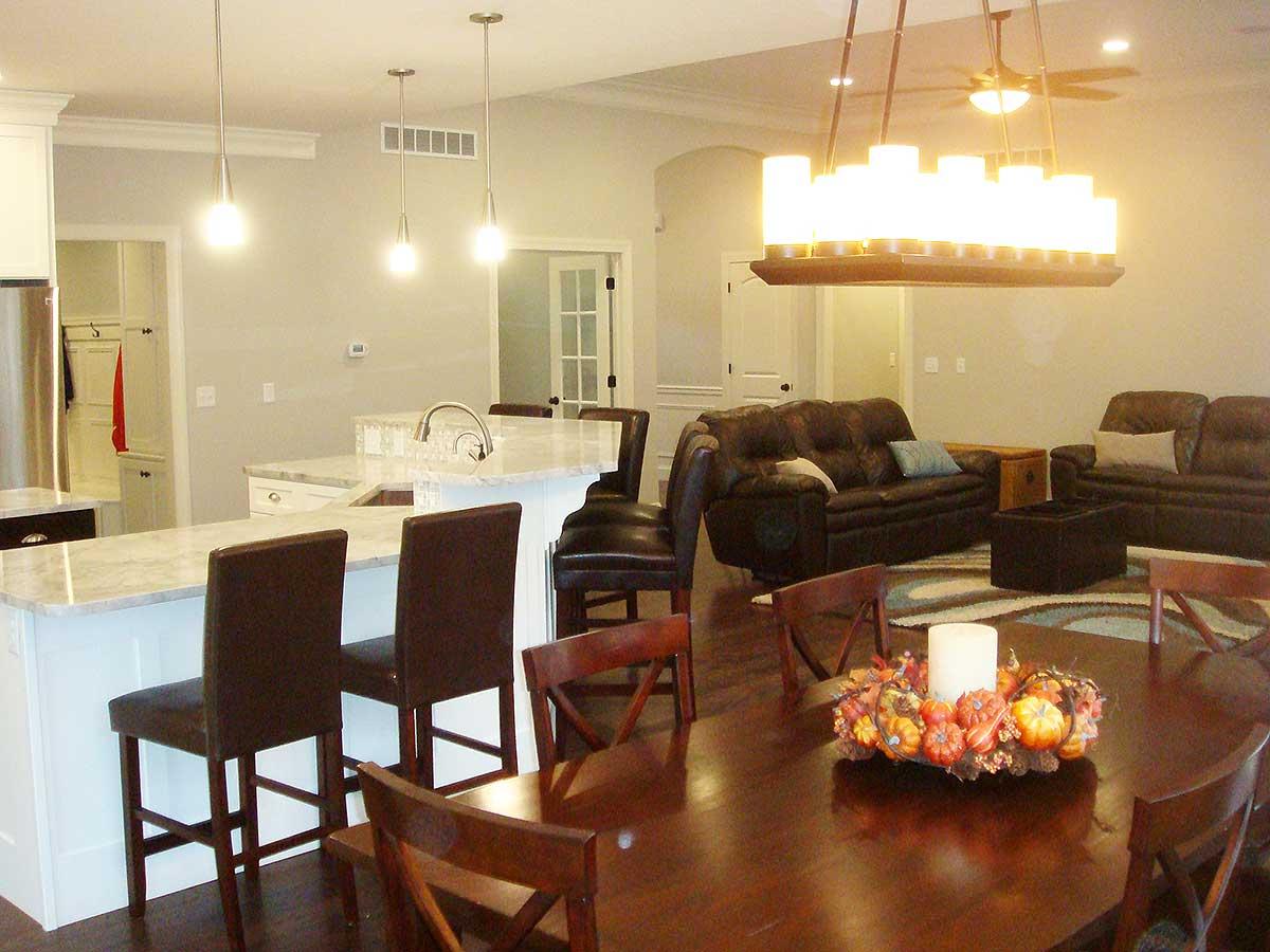 Open concept great room with island kitchen, leather sofas, dining table, and decorative fall centerpiece.