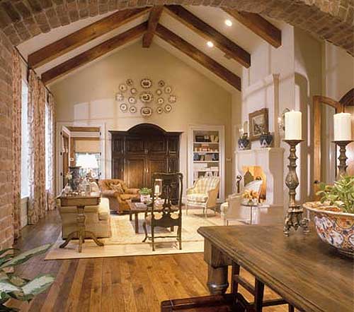 Interior view of a living room with vaulted ceiling, exposed beams, fireplace, and built-in shelving.