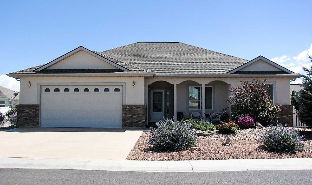 Ranch style house plan exterior with garage, arched entryway, gables, and decorative brick accents.