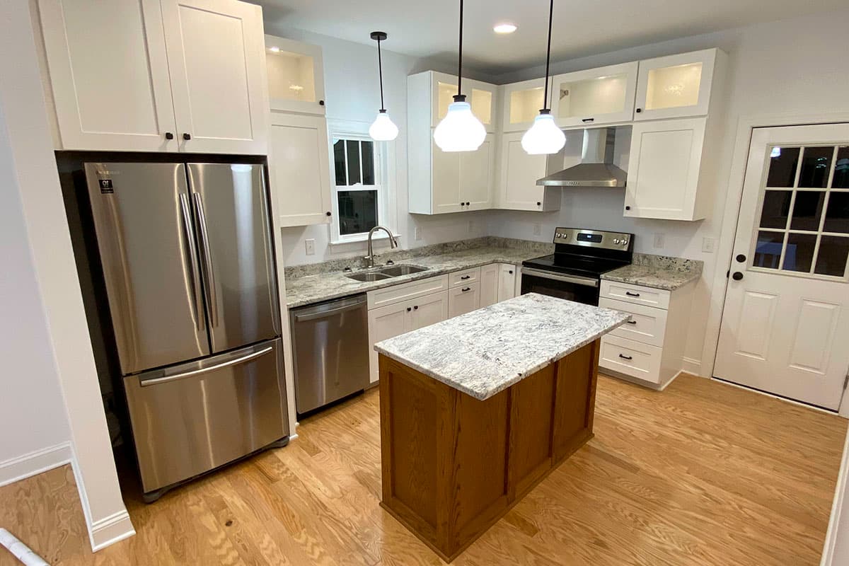 Kitchen with white cabinets, granite countertops, stainless steel appliances, island, and hardwood floors.