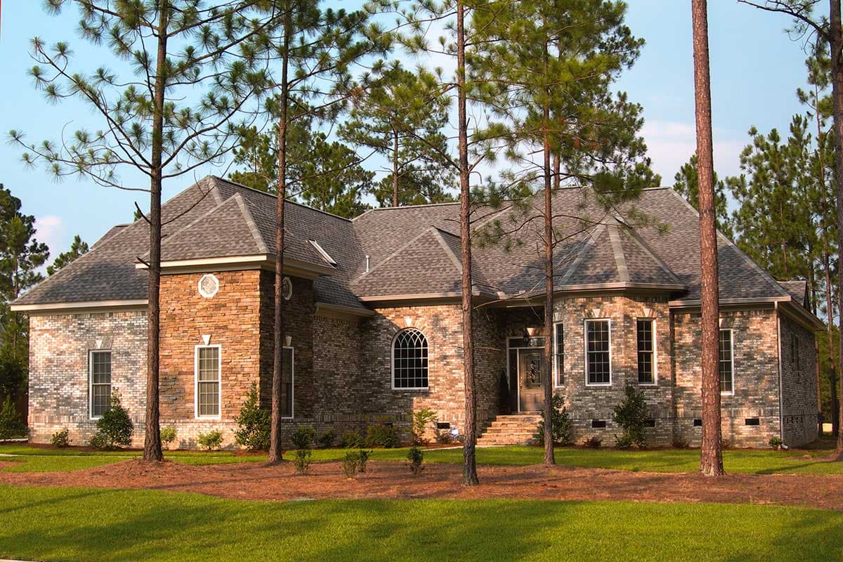 House plan exterior of a one-story brick home with stone accents, multiple gables, arched window, and covered entry.