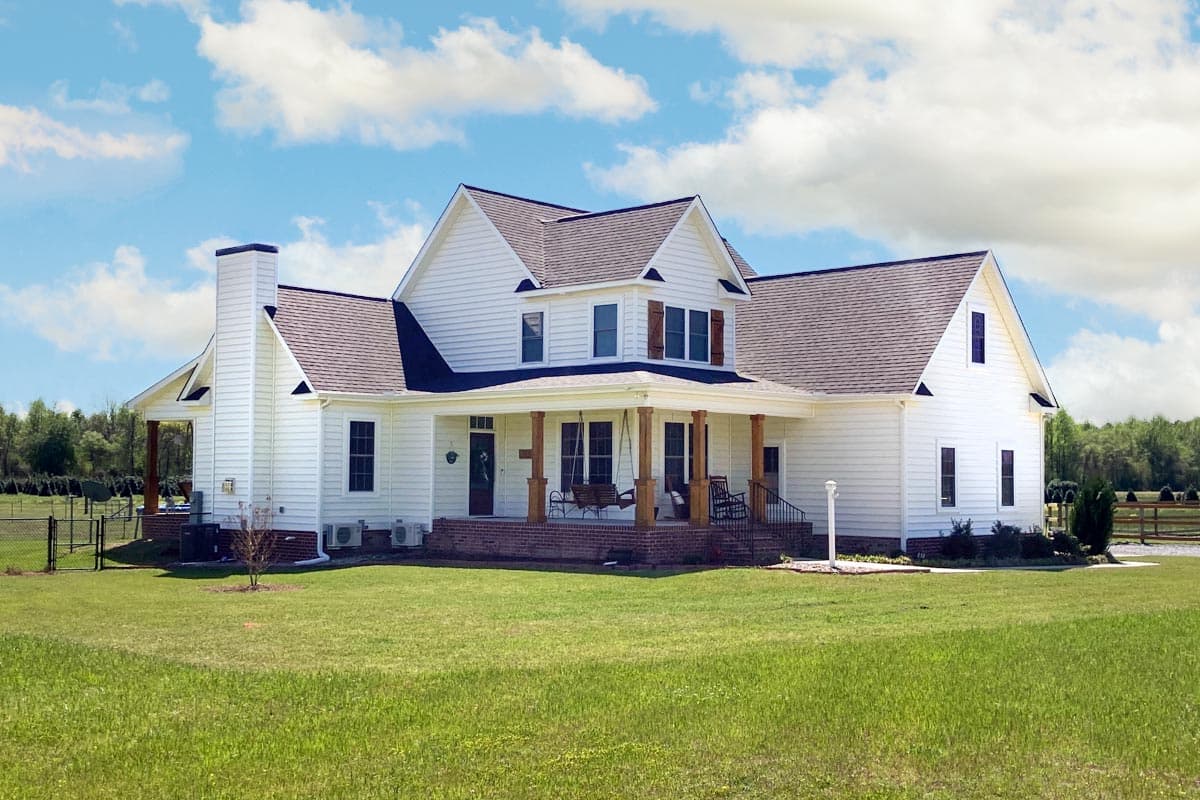 House plan exterior. Two-story farmhouse with front porch supported by columns, gabled roof, dormers, and a chimney.