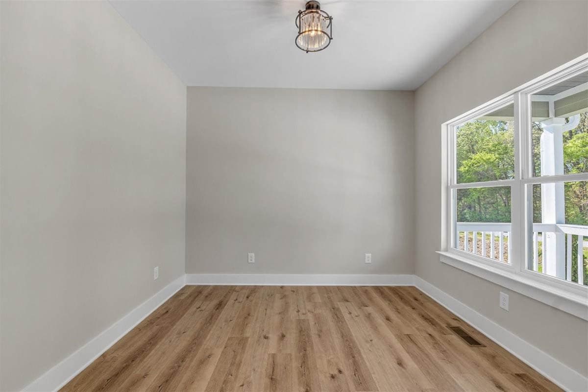 Interior view of a room with wood-look flooring, light gray walls, a large window, and a decorative ceiling light.