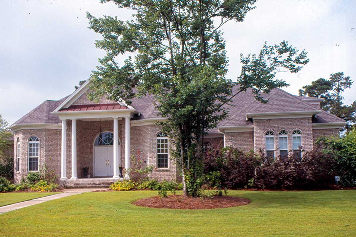 House plan exterior of a one-story brick home with a prominent portico supported by columns, arched windows, and a hip roof.