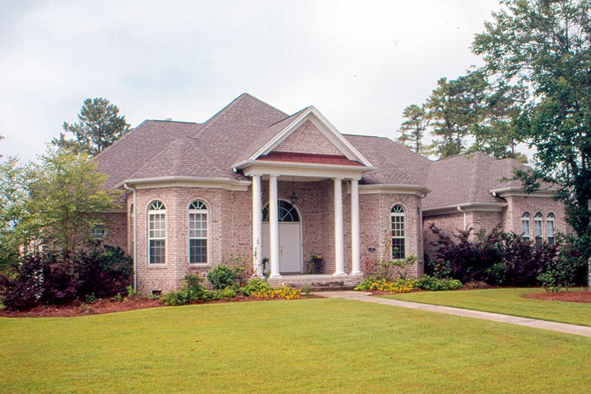 House plan exterior: One-story brick home with a prominent portico, arched windows, and varied rooflines.
