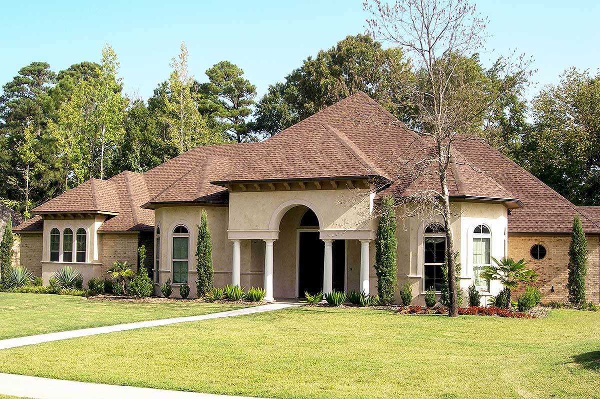 House plan exterior with a stucco finish, arched windows, multiple gables, and a prominent portico supported by columns.
