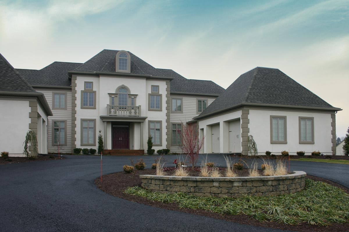 House plan exterior featuring a two-story main residence with a balcony, arched window, and attached three-car garage.