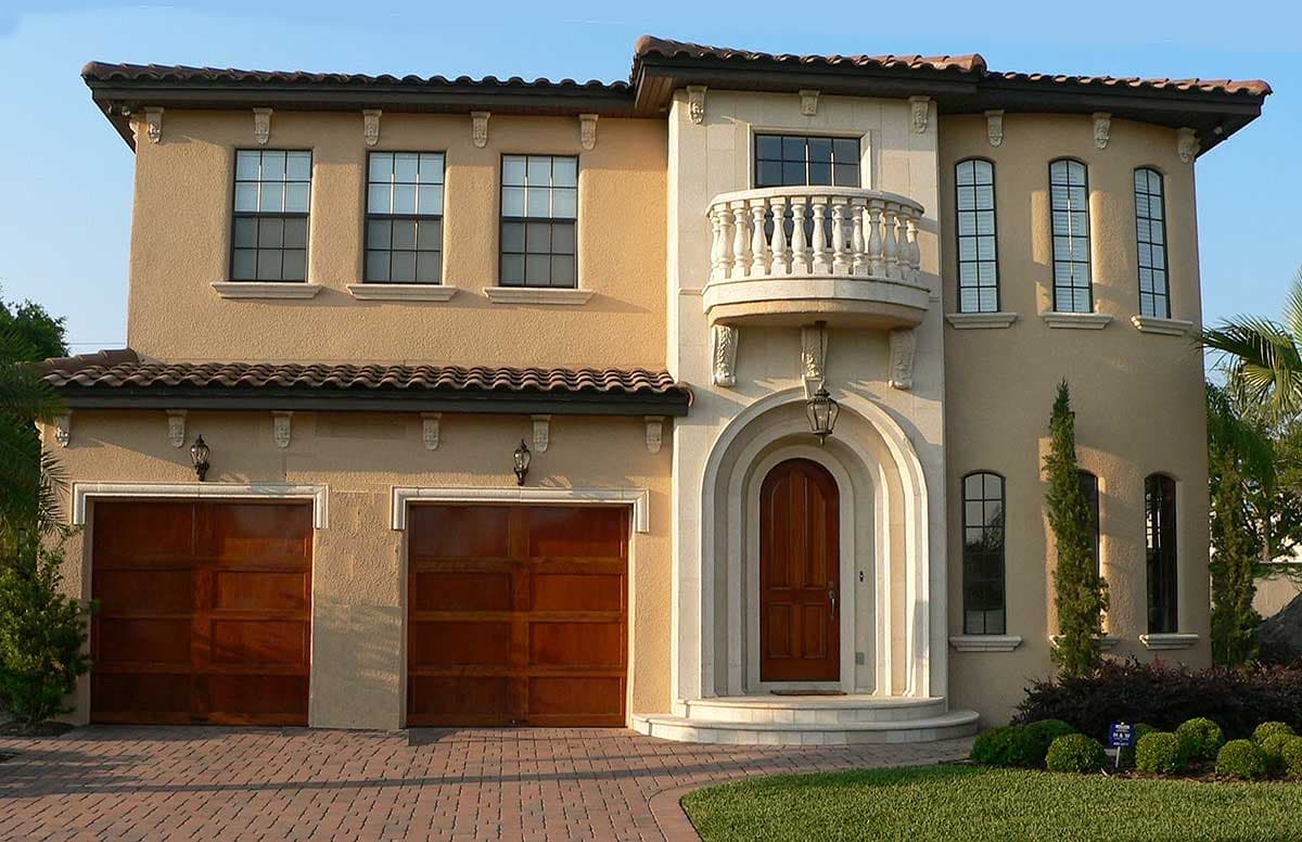 Two-story house plan exterior with arched entry, Juliet balcony, and a two-car garage.
