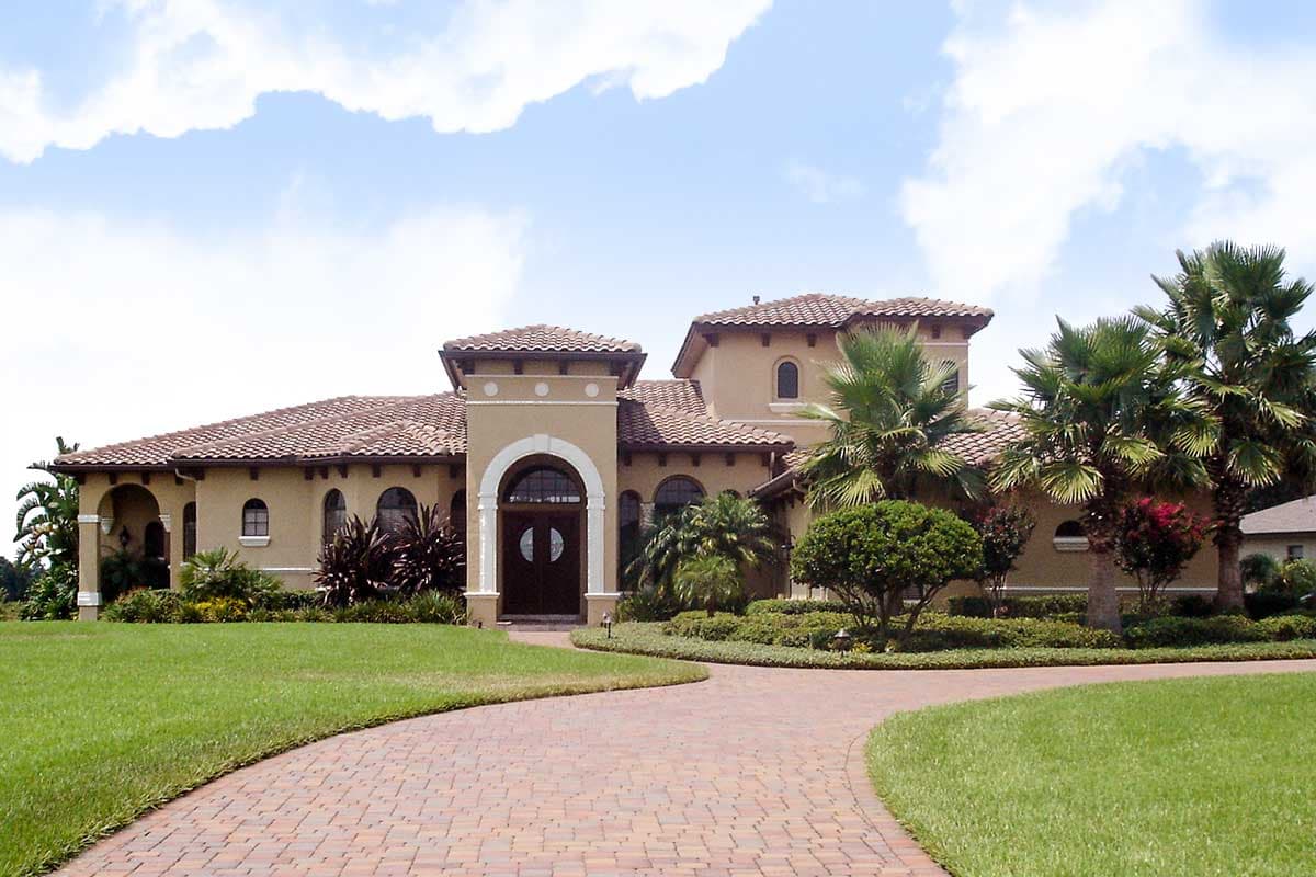 Mediterranean style house plan exterior with arched entry, tile roof, and multiple gables.