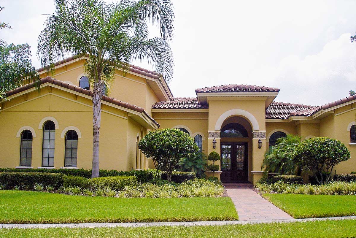 House plan exterior: Mediterranean style, one-story, with arched entryway, tile roof, and arched windows.