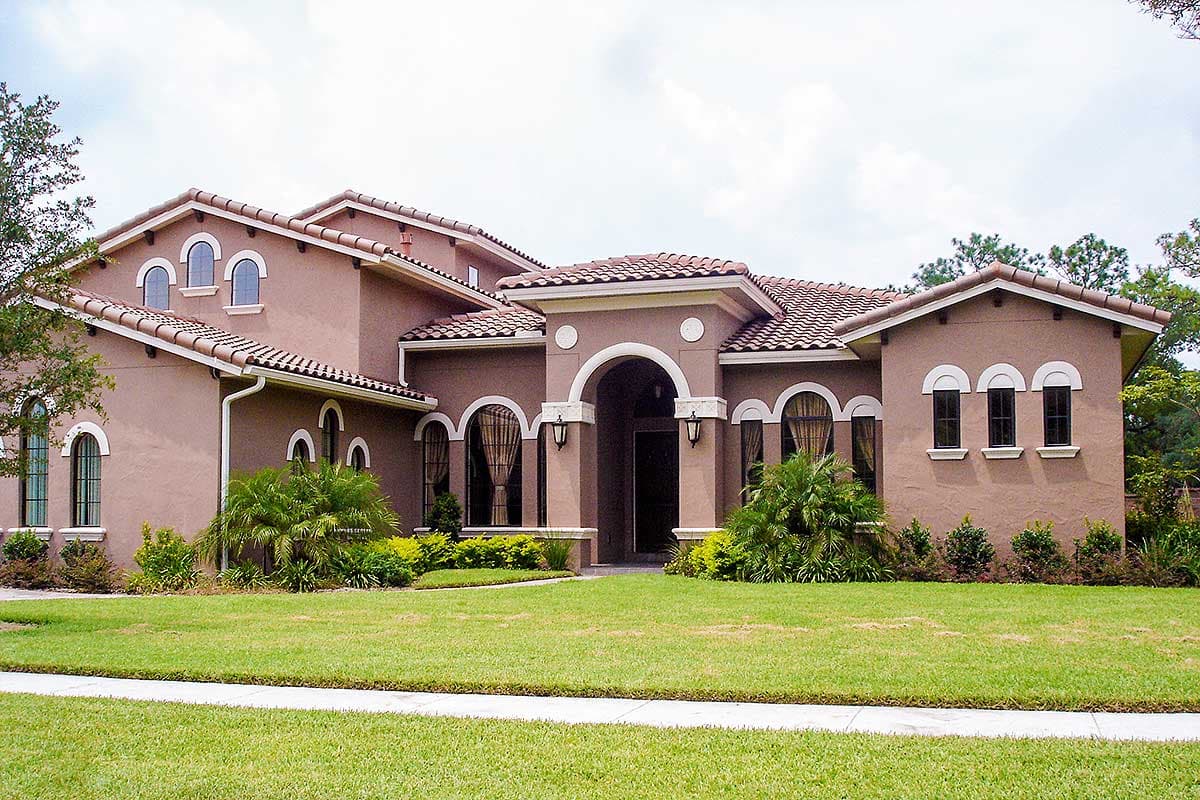House plan exterior with arched windows, a prominent arched entryway, and a tile roof.