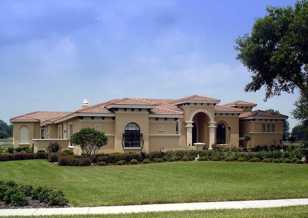 House plan exterior: Mediterranean style, one story, with arched entryway, tile roof, and stucco facade.