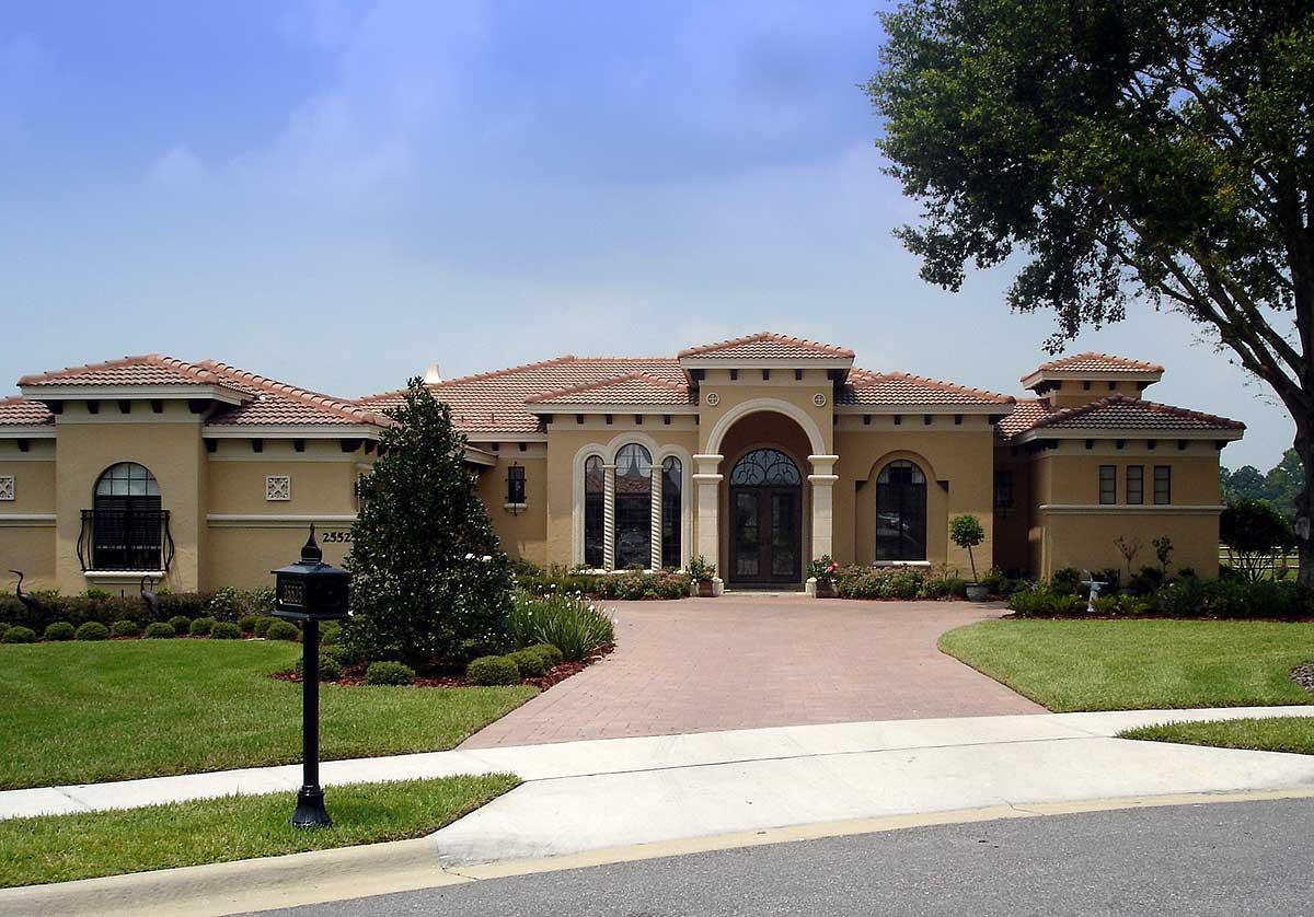 House plan exterior: Mediterranean style, one story, arched entryway, tile roof, multiple gables, and attached garage.