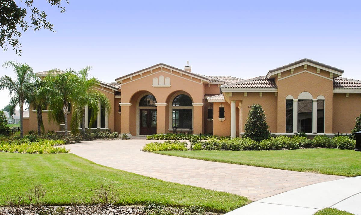 House plan exterior with stucco walls, tile roof, arched entry, and multiple gables.