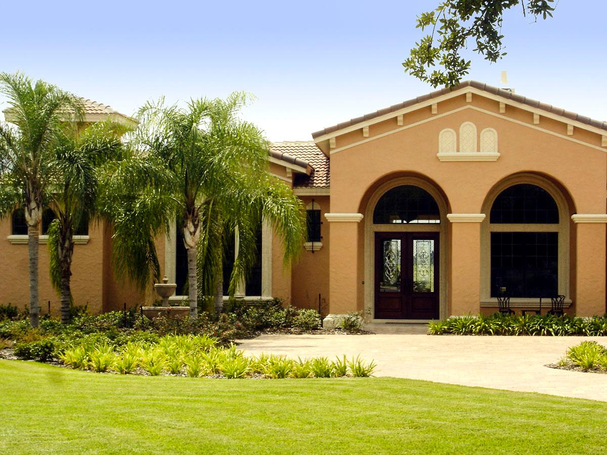 House plan exterior: Spanish-style home with arched entry, double doors, and large windows.