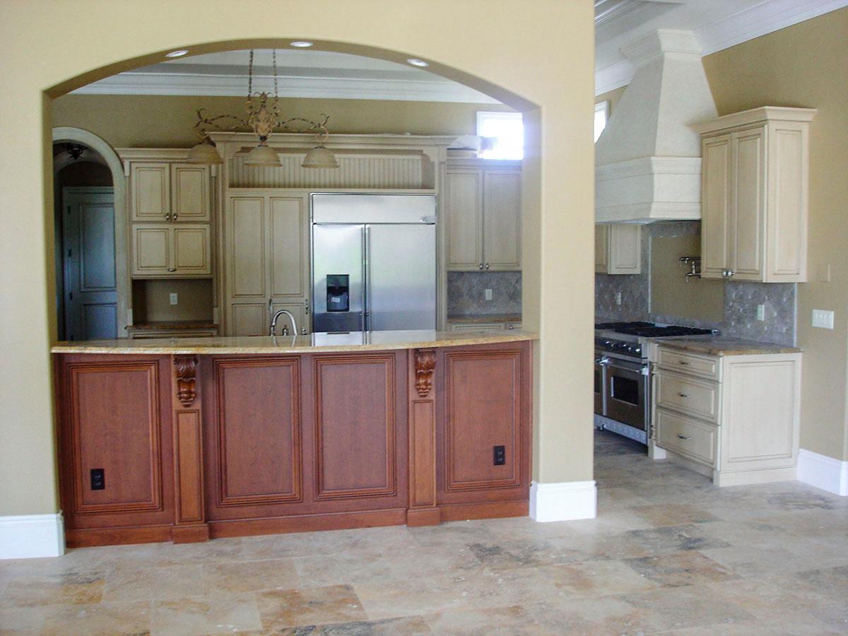 Kitchen with custom wood cabinetry, stainless steel refrigerator, granite countertops, and range hood.