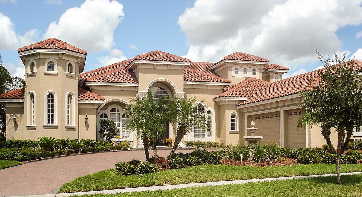 Mediterranean style house plan exterior with a prominent turret, red tile roof, arched windows, and a three-car garage.
