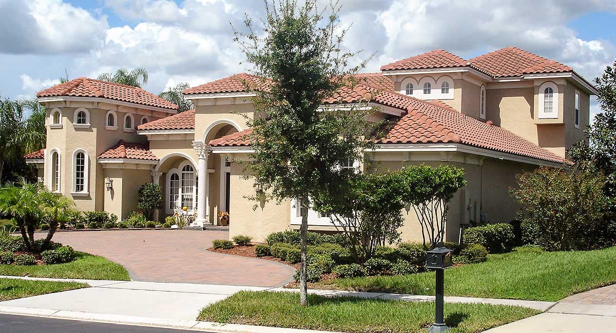 House plan exterior: Mediterranean style, two-story, stucco facade, arched windows, tile roof, prominent entryway with columns.