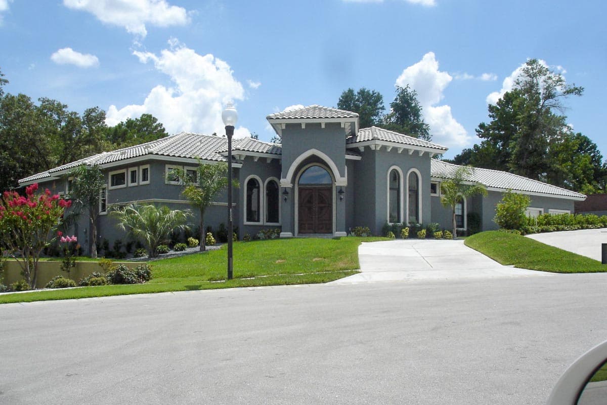 House plan exterior of a single-story stucco home with a tile roof, arched entryway, and multiple arched windows.