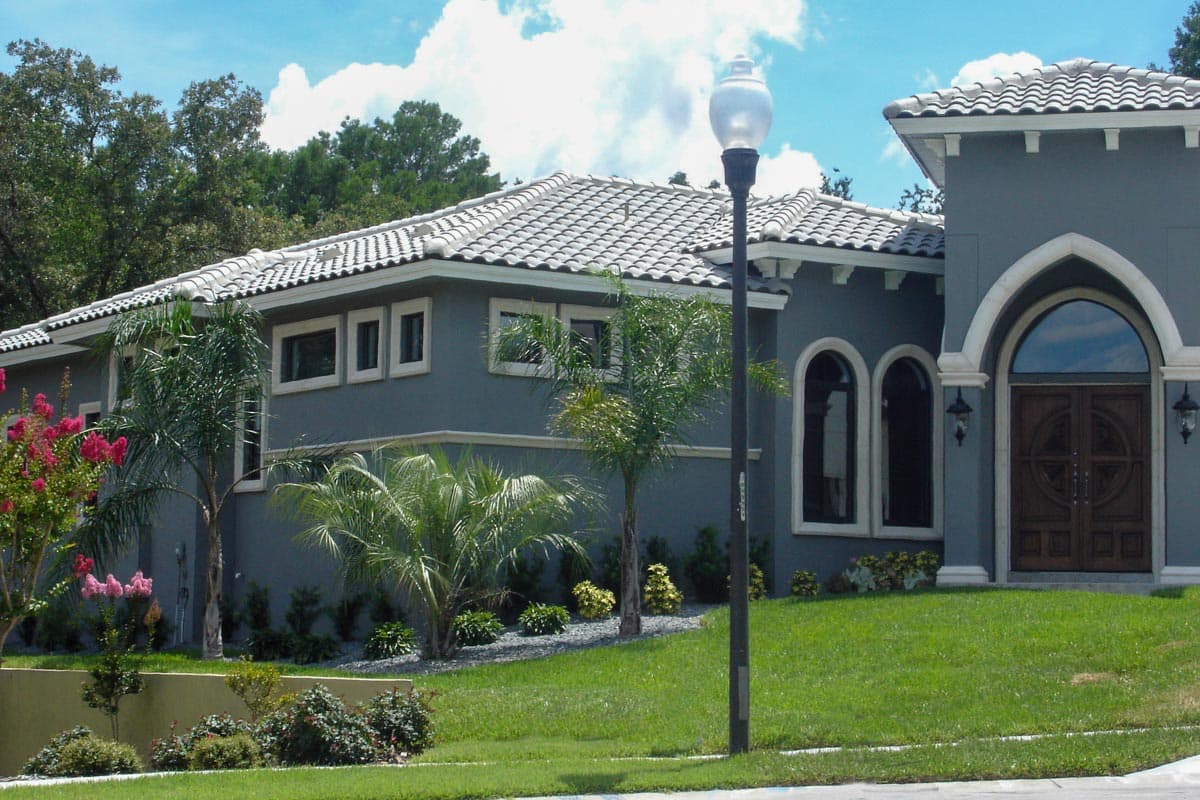 House plan exterior with stucco walls, tile roof, arched entryway, and multiple windows.