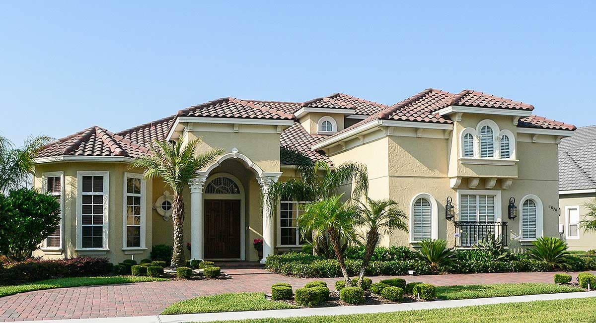 House plan exterior: Mediterranean style, two stories, arched entry, multi-level rooflines, and arched windows.