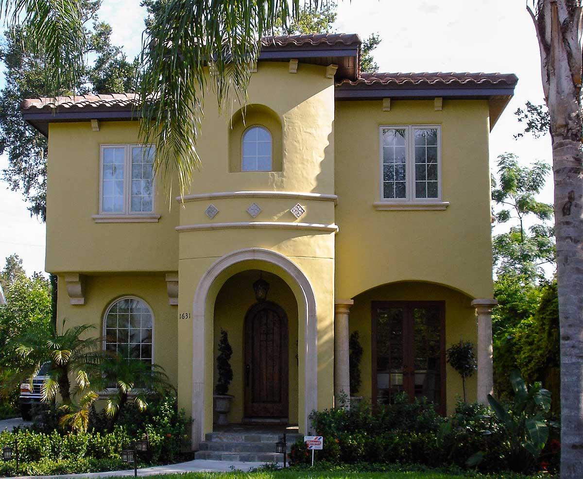 House plan exterior of a two-story Mediterranean-style home with arched entryway, rounded tower, and tile roof.